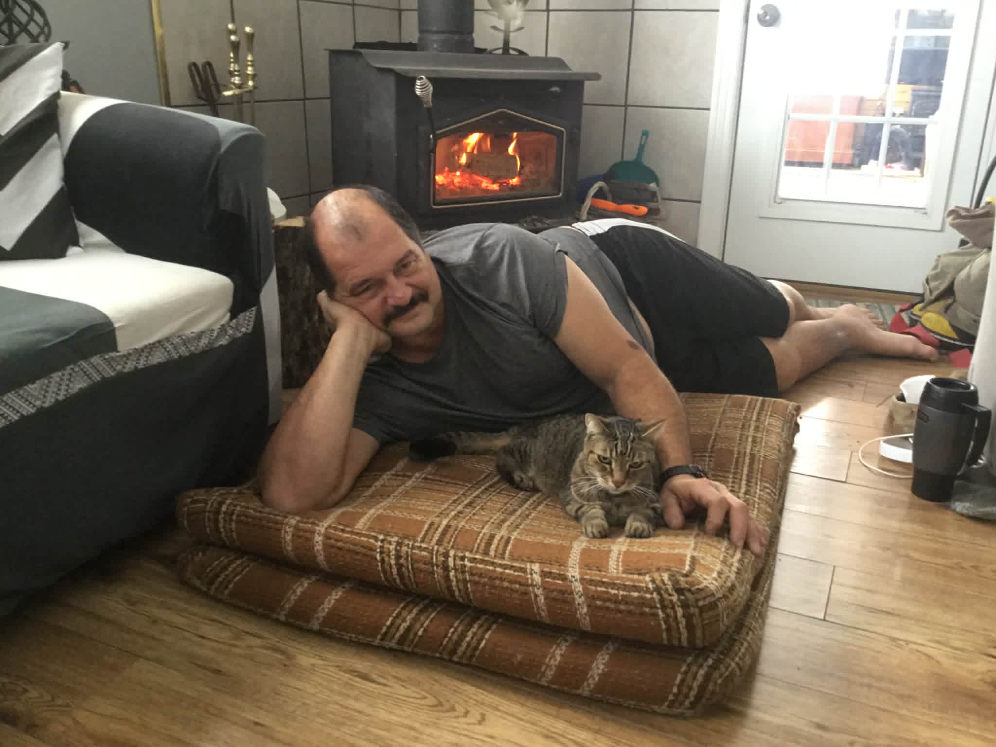 Chris by the wood stove with his cat